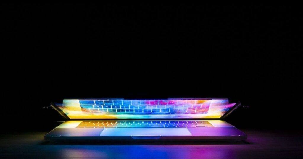 Colorful light shining from a partially open laptop in a dark room, symbolizing online income opportunities and affiliate marketing for beginners.